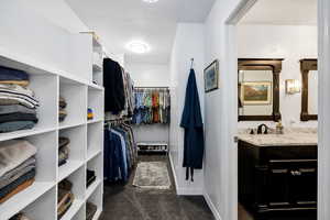 Master Spacious closet with dark carpet and a sink