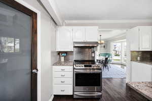 Kitchen with stainless steel range with electric cooktop, white cabinets, light stone countertops, dark wood finished floors, and crown molding