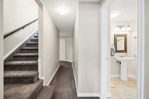 Stairway featuring tile patterned flooring, a textured ceiling, and carpet
