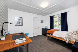 Bedroom featuring dark colored carpet, coffered ceiling, a desk, and beamed ceiling