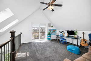 Loft area featuring high vaulted ceiling, carpet floors, a ceiling fan, a skylight, and healthy amount of natural light