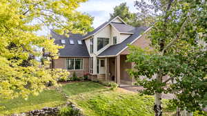 View of front of home with a front lawn, roof with shingles, and brick siding