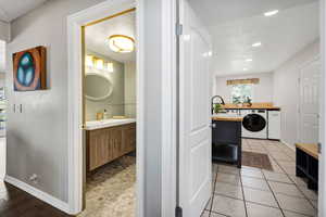 Bathroom featuring vanity, washer / dryer, a textured ceiling, light tile patterned floors, and recessed lighting