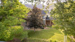 Exterior space with a mountain view, a lawn, brick siding, and a shingled roof