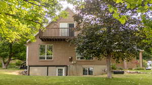 Back of house with brick siding, a yard, and a balcony