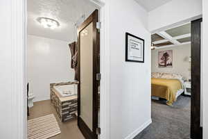 Master Bedroom Corridor with coffered ceiling, beamed ceiling, a textured ceiling, and dark carpet