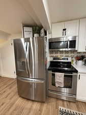 Kitchen featuring appliances with stainless steel finishes, white cabinetry, and light wood-style flooring