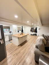 Kitchen featuring butcher block counters, white cabinetry, stainless steel appliances, open floor plan, and light wood finished floors