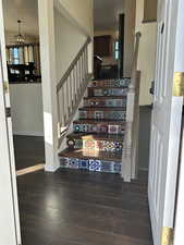 Staircase with hardwood / wood-style floors and a chandelier