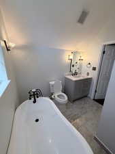 Bathroom with a freestanding tub, vanity, and vaulted ceiling