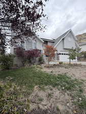 View of front of home with roof mounted solar panels, a front yard, and a shingled roof
