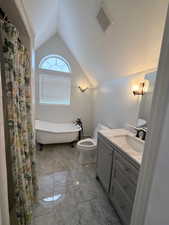Bathroom featuring vaulted ceiling, vanity, a freestanding bath, and curtained shower