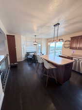 Kitchen with a kitchen bar, decorative light fixtures, light countertops, a kitchen island, and a textured ceiling