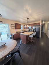 Kitchen featuring light countertops, a kitchen island, appliances with stainless steel finishes, pendant lighting, and a textured ceiling