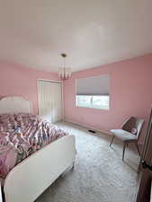 Carpeted bedroom with a closet and a chandelier