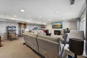 Living room with a textured ceiling, a fireplace, carpet, recessed lighting, and wood walls