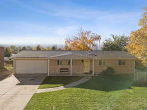 Ranch-style home featuring a porch, a front yard, brick siding, driveway, and roof with shingles
