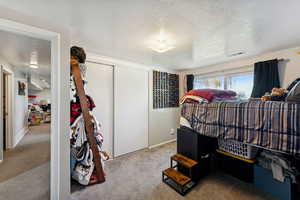 Bedroom featuring a textured ceiling, carpet floors, and a closet