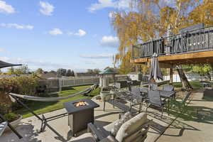 Fenced backyard with outdoor dining area, a patio area, an outdoor fire pit, a deck, and a grill
