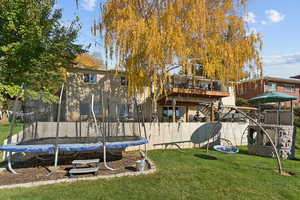 Back of house featuring a trampoline and a playground