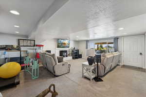 Living room featuring light colored carpet, recessed lighting, a glass covered fireplace, and a textured ceiling