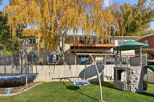 Rear view of house featuring a trampoline, brick siding, and a playground