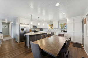 Dining room featuring a textured ceiling, dark wood-type flooring, and recessed lighting