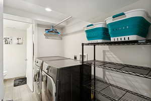 Washroom featuring washing machine and clothes dryer, light wood finished floors, and recessed lighting