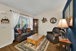 Living room featuring dark wood-style flooring and lofted ceiling