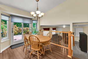Dining space with wood finished floors, a chandelier, and lofted ceiling