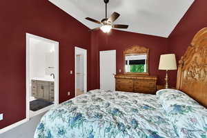 Bedroom with light carpet, ensuite bathroom, ceiling fan, and high vaulted ceiling