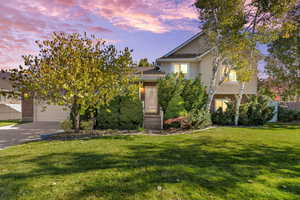 View of front of property with brick siding, concrete driveway, and stucco siding