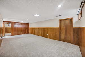 Finished below grade area with carpet flooring, recessed lighting, wood walls, and a wainscoted wall