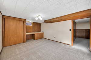 Below grade area with wood walls, light carpet, and a desk