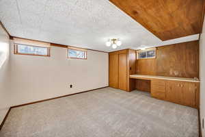 Unfurnished bedroom featuring healthy amount of natural light, built in desk, and light carpet
