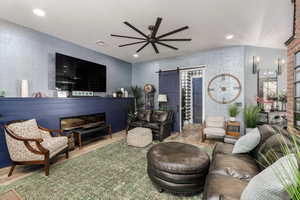 Living room featuring a barn door leading to laundry, wood tile finished floors, a ceiling fan, and recessed lighting
