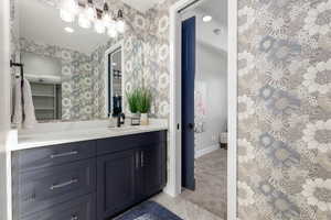 Jack & Jill bathroom leading to Bedroom #3, featuring vanity, light carpet, light tile patterned flooring, and wallpapered walls