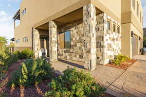 Doorway to property featuring stone siding and stucco siding