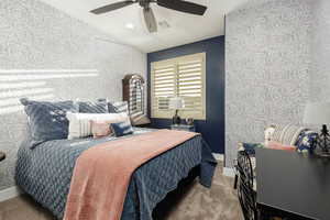 Bedroom #5 featuring wallpapered walls, an accent wall, a ceiling fan, carpet flooring, and vaulted ceiling