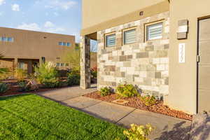 Doorway to property featuring stucco siding and a lawn