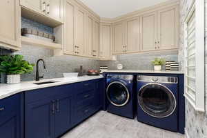 Washroom with light tile patterned flooring, washer and clothes dryer, and cabinet space