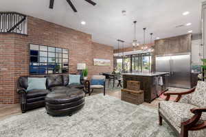 Living room featuring brick wall, light wood-style flooring, recessed lighting, and a chandelier