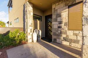 Doorway to property featuring stone siding, a patio area, and stucco siding