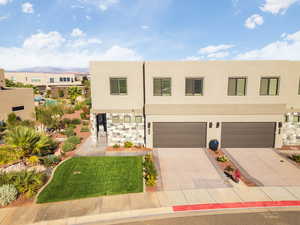 Modern home featuring driveway, stucco siding, a front yard, and a garage