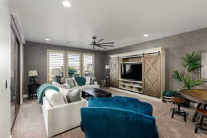 Carpeted living room with wallpapered walls, a sliding door, a ceiling fan, and recessed lighting