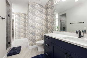 Jack & Jill Bathroom featuring a shower stall, vanity, recessed lighting, and wallpapered walls