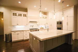 Kitchen featuring hanging light fixtures, light stone counters, dark wood-type flooring, and recessed lighting