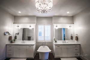 Bathroom featuring two vanities, a freestanding tub, dark wood-style flooring, a chandelier, and recessed lighting