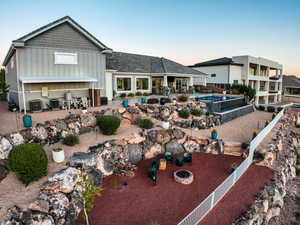 Back of property at dusk with a patio, board and batten siding, a fenced backyard, an outdoor fire pit, and an outdoor pool