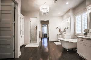 Full bath with vanity, dark wood finished floors, a stall shower, a chandelier, and a soaking tub